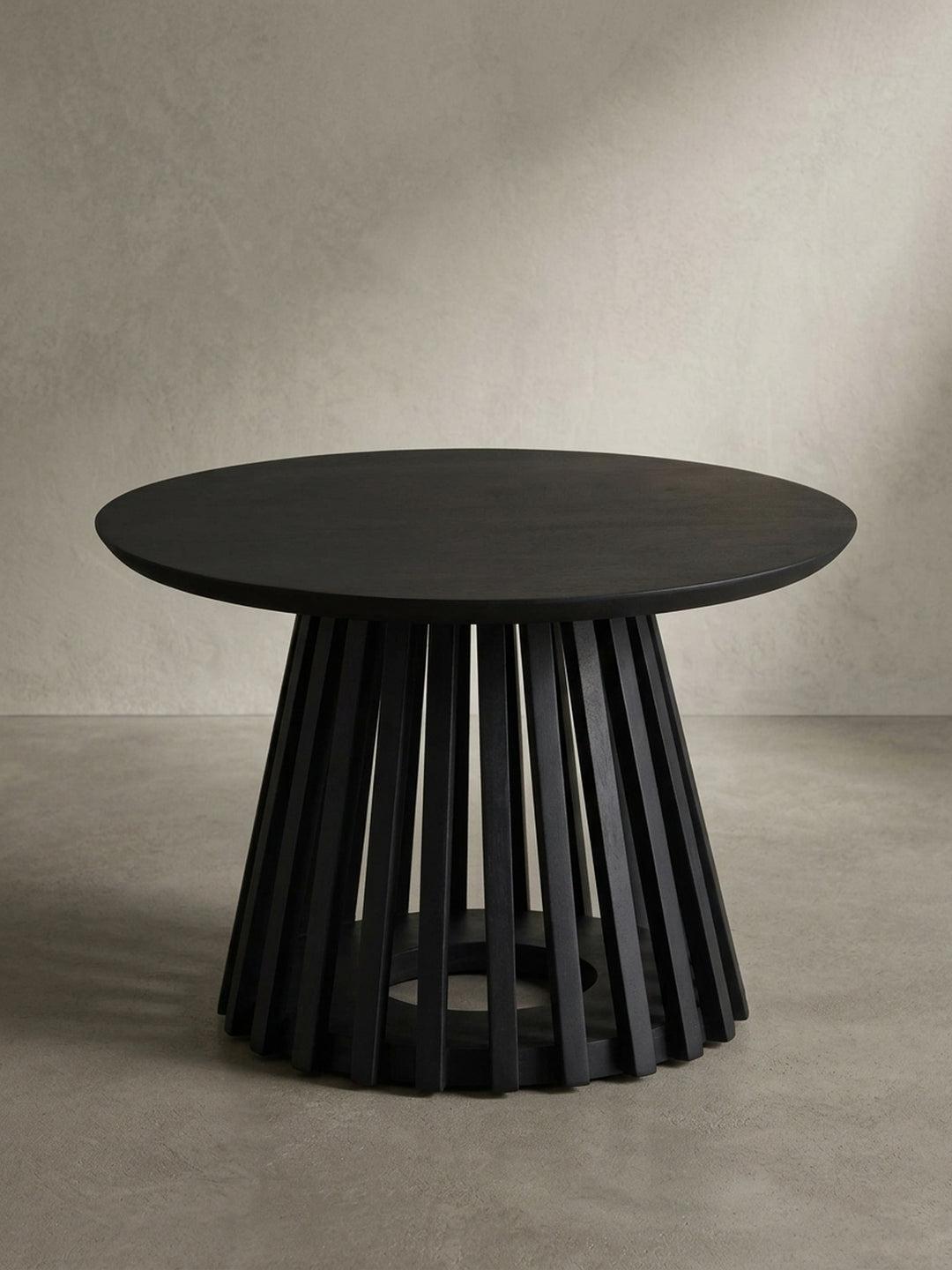 Freigestellte Frontansicht des runden Couchtischs in Schwarz, der die massive Tischplatte und das skulpturale Gittergestell aus Mangoholz zeigt._