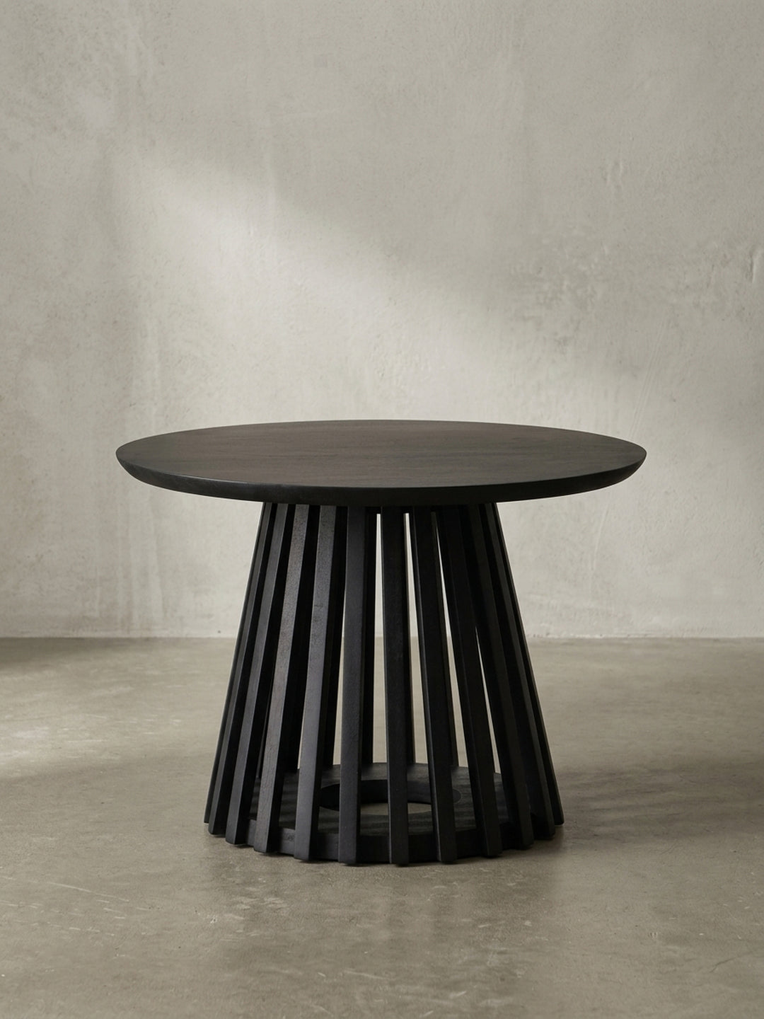 Gesamtansicht des runden Mangoholz-Couchtisches in Schwarz, dessen zeitloses Design mit offenem Gestell Eleganz und Leichtigkeit vermittelt._