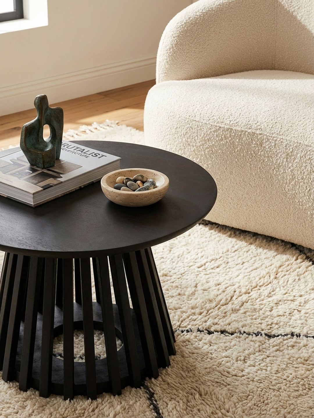 Moderner Wohnzimmertisch in Schwarz, dekoriert mit einem Chanel-Bildband und einer abstrakten Skulptur, für ein stilvolles Ambiente._