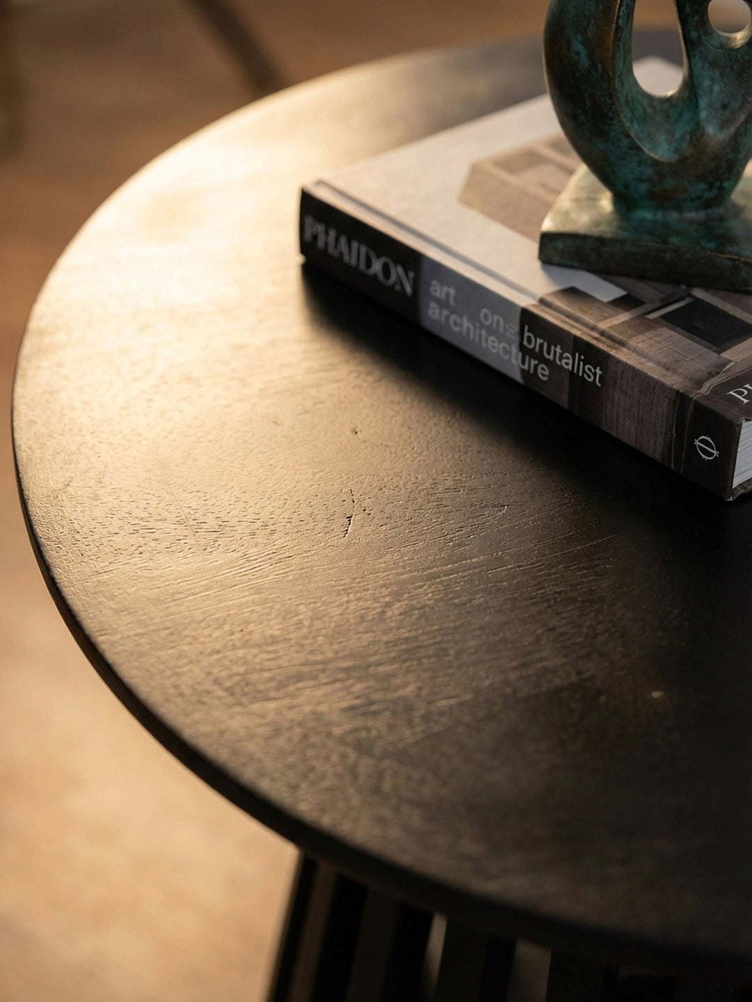 Detailaufnahme der schwarz lackierten Massivholz-Oberfläche des Kaffeetisches, die feine, natürliche Maserung des Mangoholzes ist dezent erkennbar._