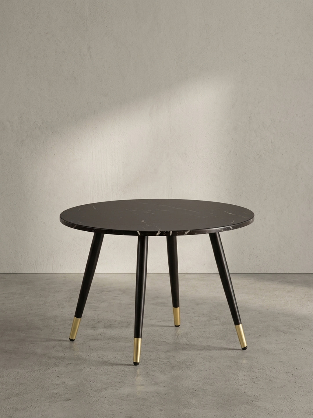 Freigestellter runder Couchtisch mit einer 60 cm breiten dunklen Marmor-Dekor-Platte und konisch zulaufenden schwarzen Metallbeinen._