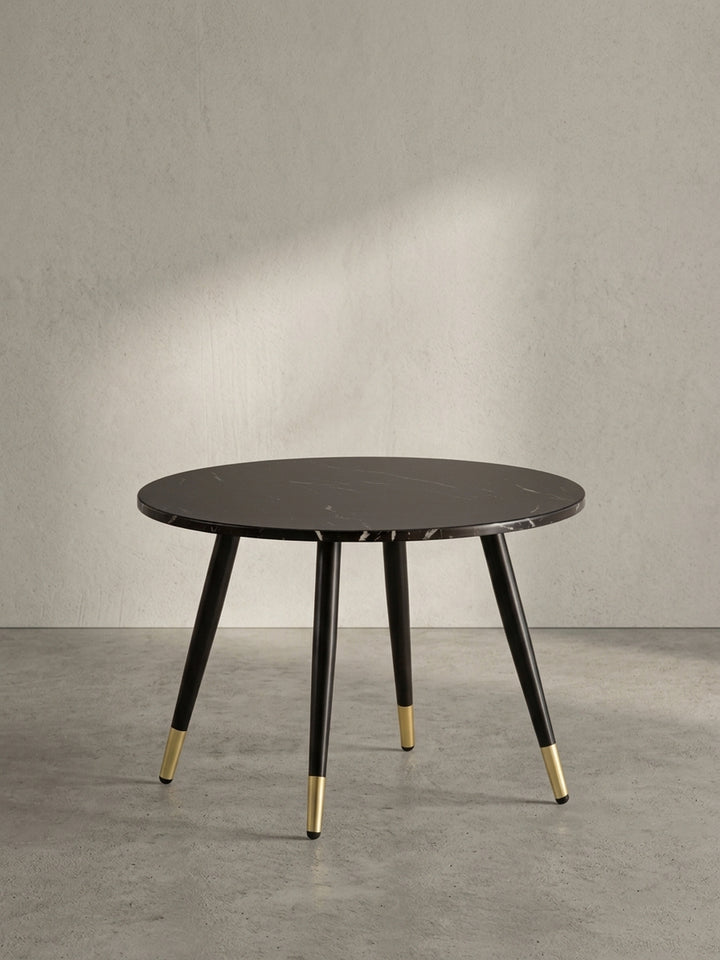 Freigestellter runder Couchtisch mit einer 60 cm breiten dunklen Marmor-Dekor-Platte und konisch zulaufenden schwarzen Metallbeinen._