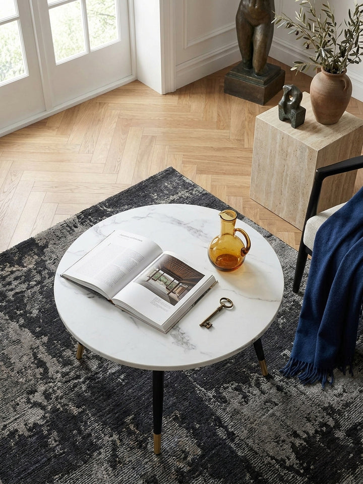 Draufsicht auf einen kleinen 60x60 cm Wohnzimmertisch in edler Marmoroptik arrangiert neben einem dunklen Samtsofa auf anthrazitfarbenem Teppich_