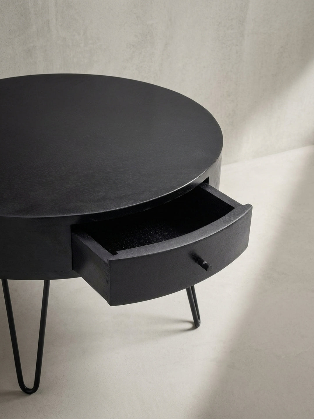 Nahaufnahme der dezenten Schublade des schwarzen Mangoholz-Couchtischs, die eleganten und versteckten Stauraum für das Wohnzimmer bietet._