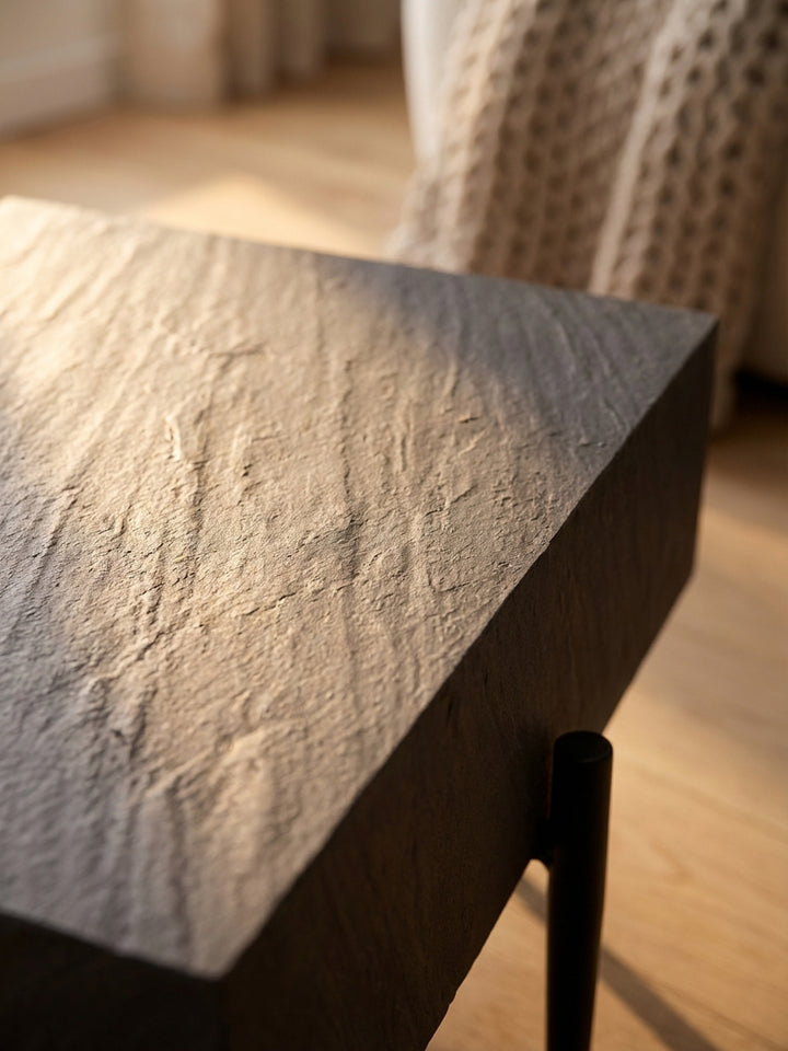 Detailaufnahme der texturierten 3D-Oberfläche des Couchtisches, die eine authentische, matte Steinoptik in dunklem Anthrazit natürlich nachbildet._