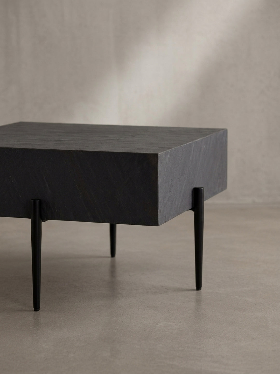 Nahaufnahme eines der schlanken, schwarzen Metallbeine des Couchtisches, das die hochwertige Pulverbeschichtung und die präzise Verarbeitung im Detail zeigt._