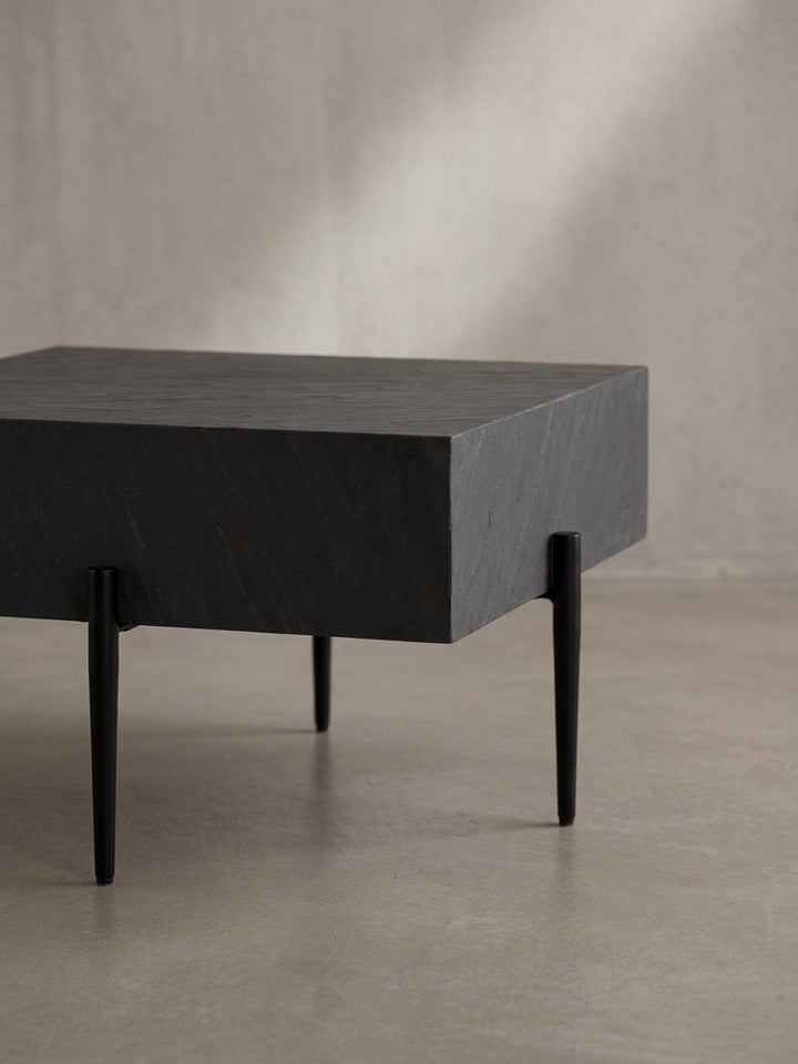 Nahaufnahme eines der schlanken, schwarzen Metallbeine des Couchtisches, das die hochwertige Pulverbeschichtung und die präzise Verarbeitung im Detail zeigt._