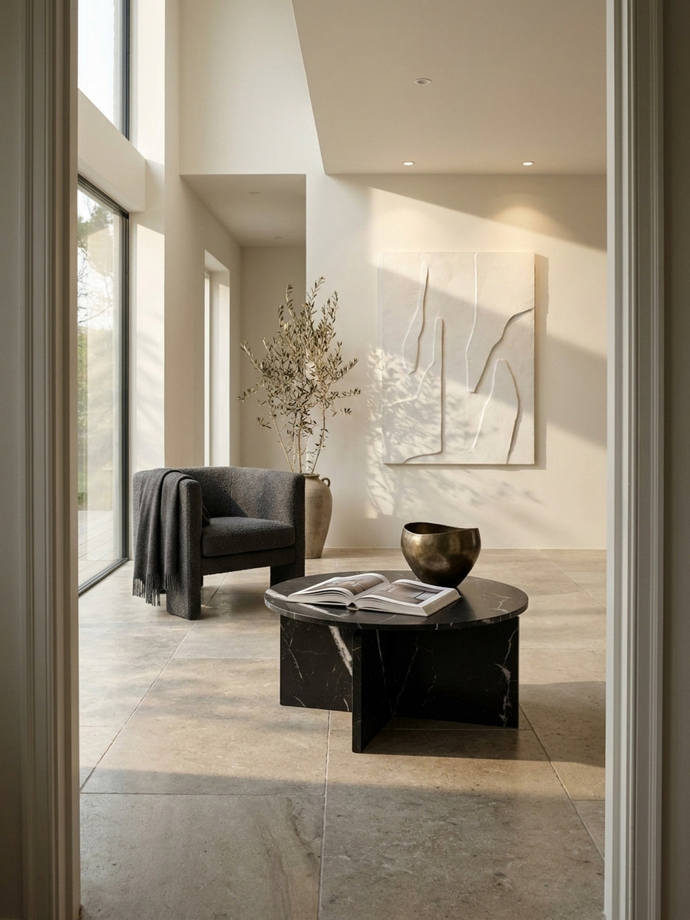 Schwarzer Couchtisch in Marmor-Optik auf hellem Kalksteinboden im minimalistischen Wohnzimmer neben einem hellen Leinensofa_