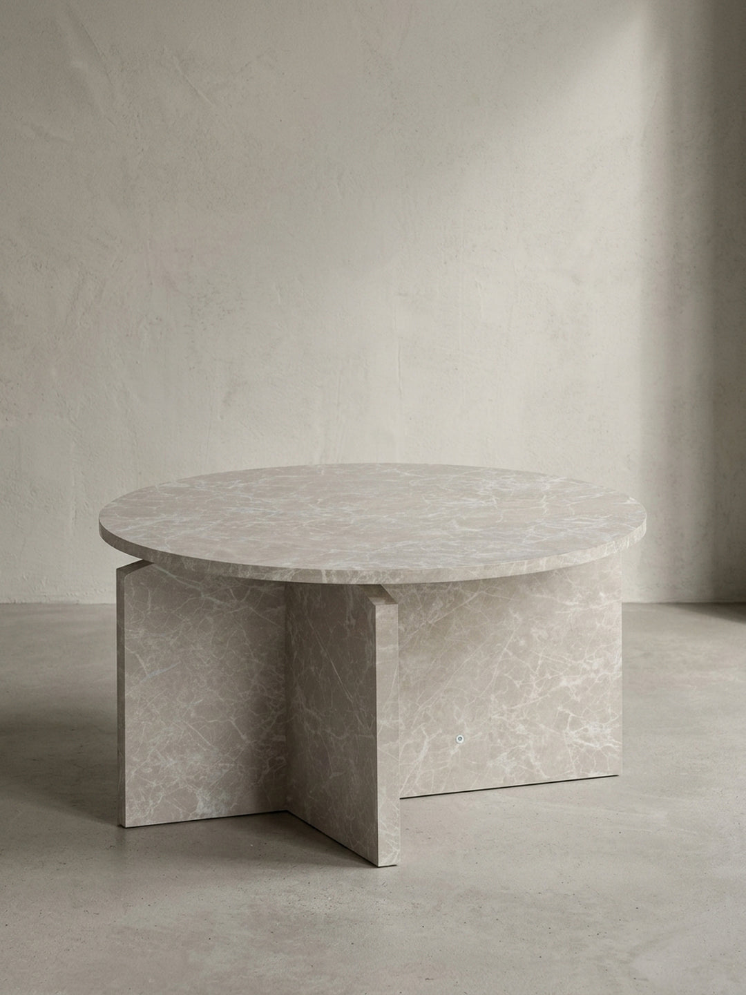 Minimalistischer Sofatisch 60x60x33 cm mit runder Tischplatte und architektonischem Kreuzgestell in heller Stein-Optik, freigestellt vor einem neutralen weißen Hintergrund._
