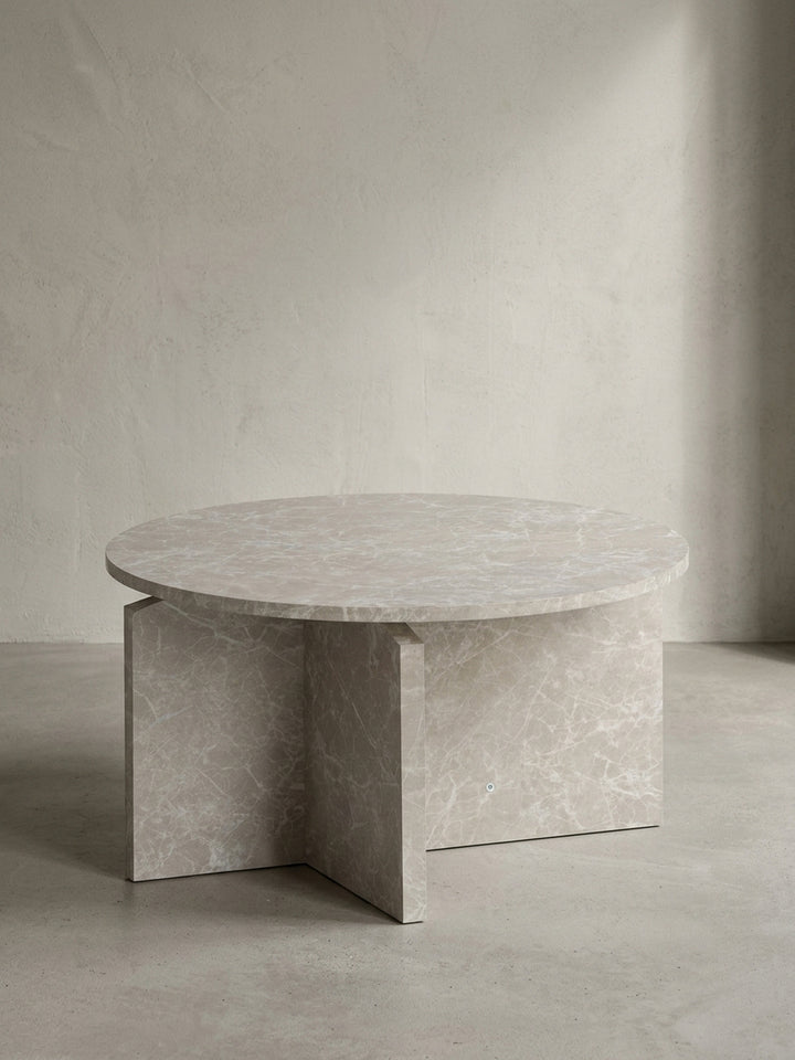 Minimalistischer Sofatisch 60x60x33 cm mit runder Tischplatte und architektonischem Kreuzgestell in heller Stein-Optik, freigestellt vor einem neutralen weißen Hintergrund._