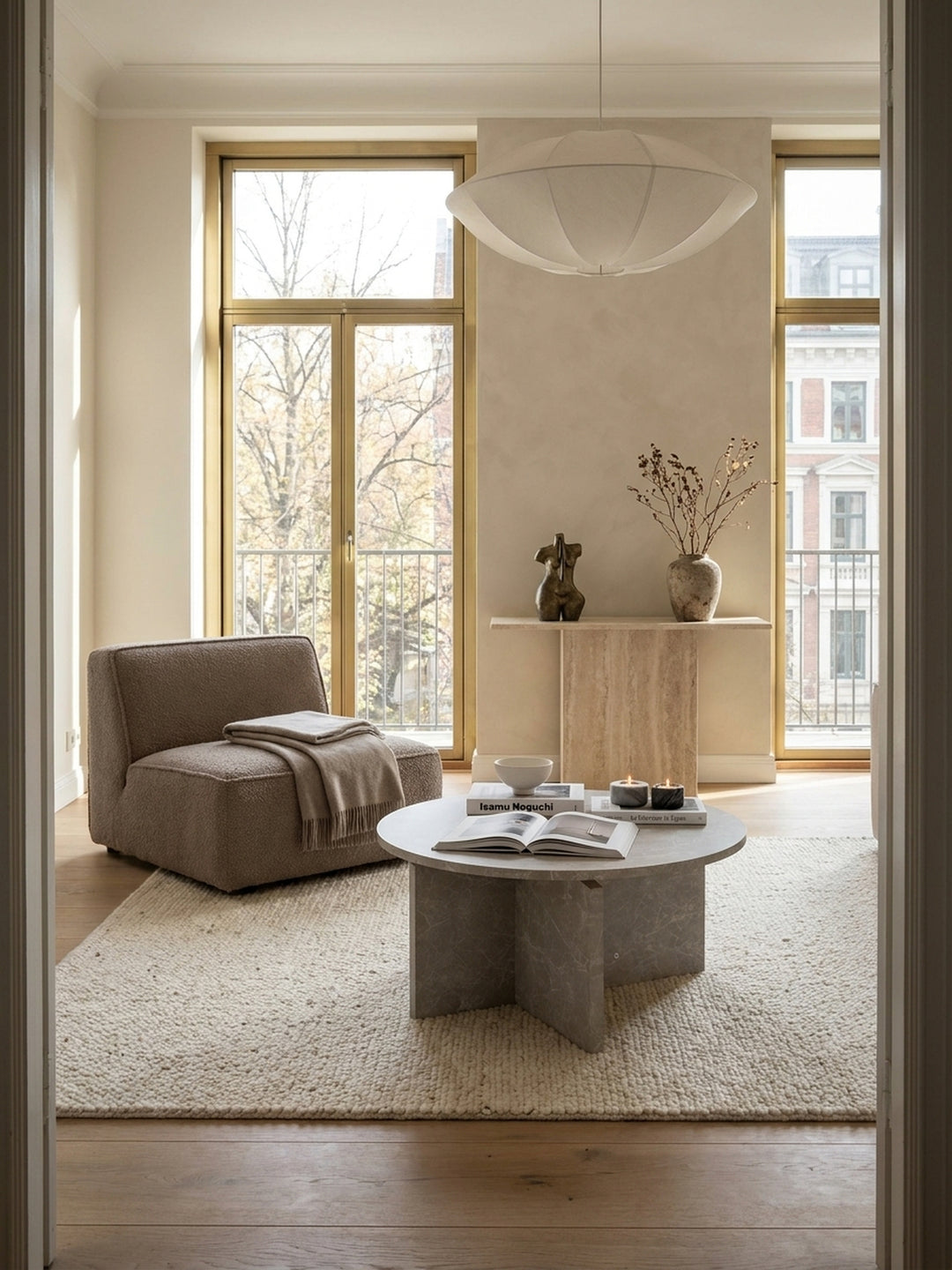 Skulpturaler Couchtisch in sandfarbener Stein-Optik 60x60 cm als Herzstück in einem luxuriösen organisch-modernen Wohnzimmer mit beigem Bouclé-Sofa und echten Eichendielen._