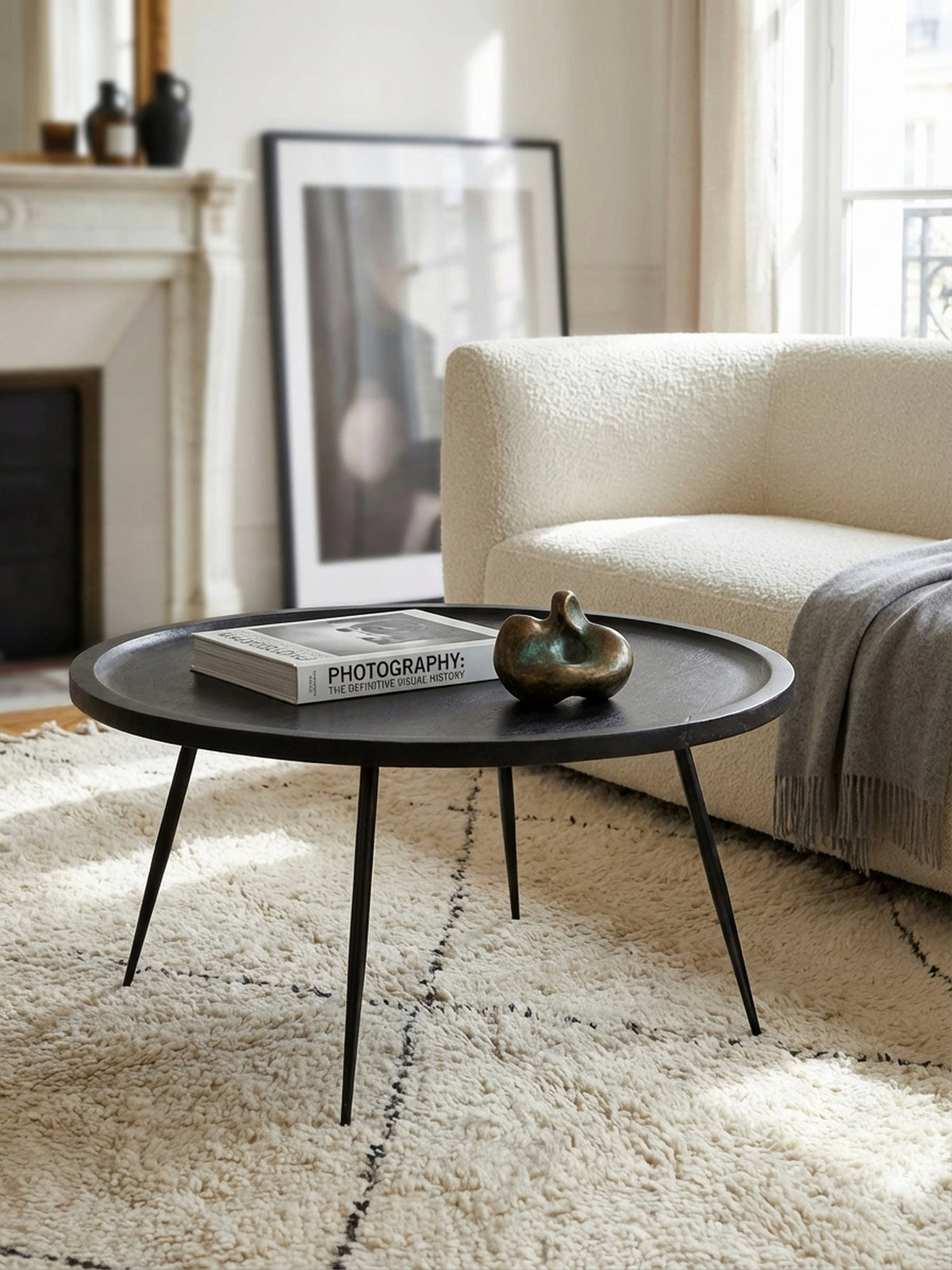 Ein Stapel Bücher und eine Tasse auf dem schwarzen Design-Couchtisch aus Mangoholz, der eine gemütliche und persönliche Atmosphäre im Wohnzimmer schafft.