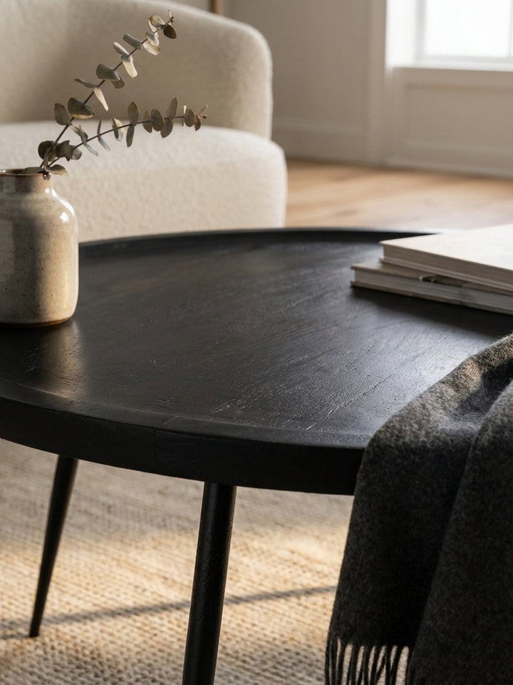 Nahaufnahme der markanten schwarzen Holzmaserung des Couchtischs aus massivem Mangoholz, die die natürliche Schönheit des Materials zeigt._