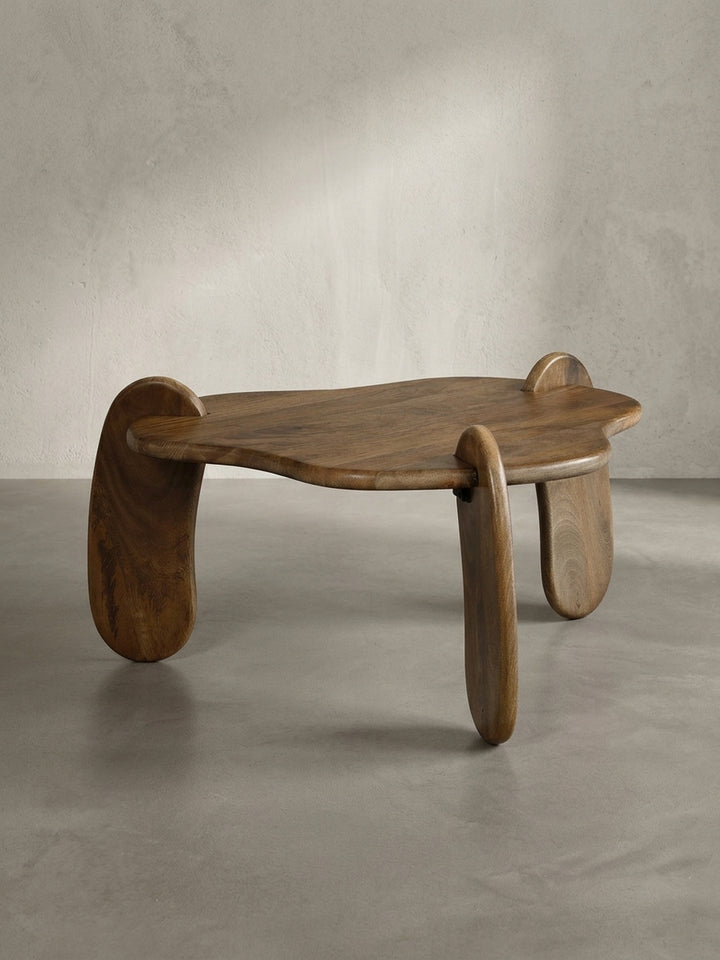Seitenprofil des niedrigen Couchtisches aus Massivholz, das seine elegante, bodennahe Statur und die geschwungene Form der Beine hervorhebt._