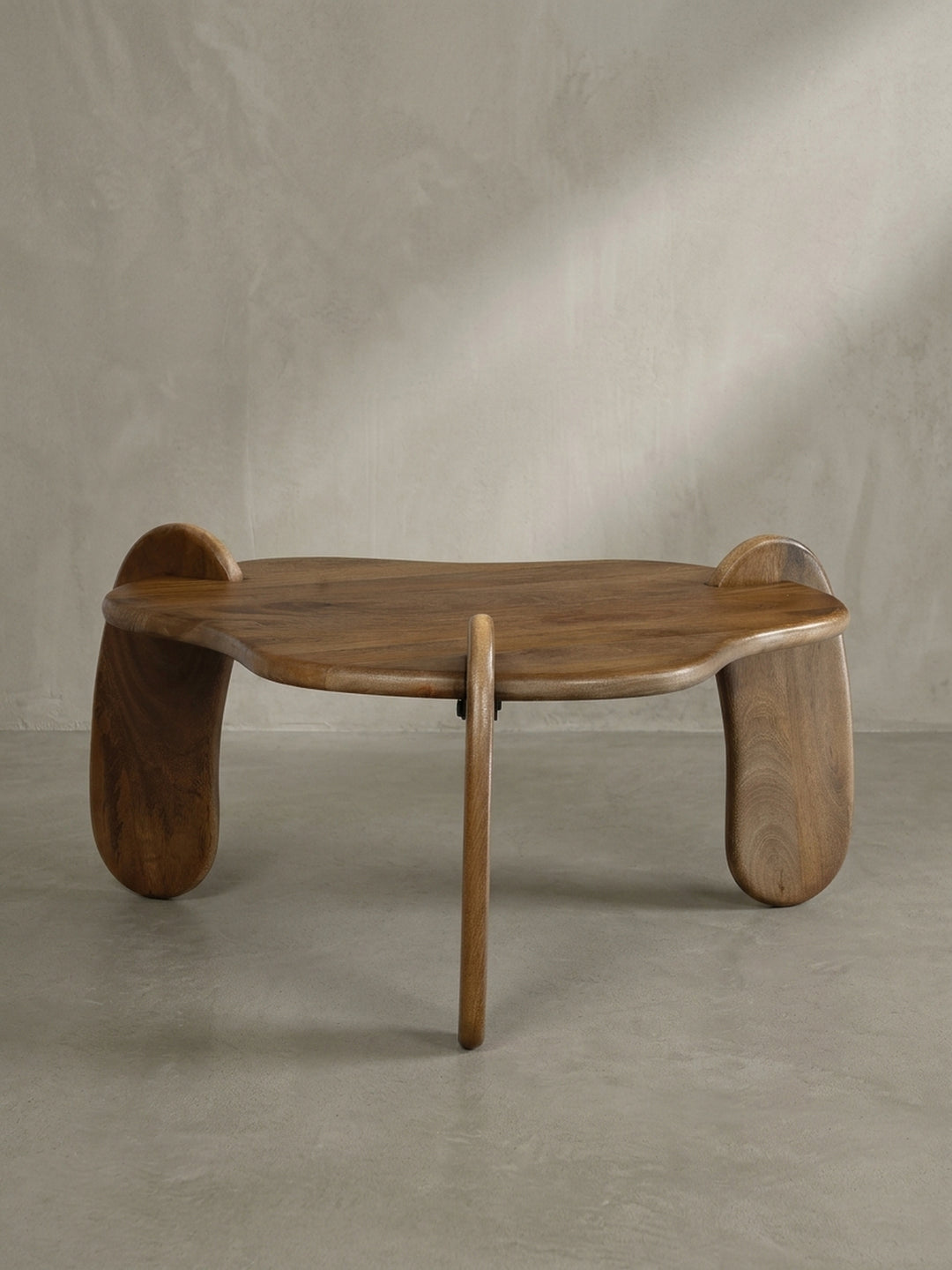 Frontansicht des Design-Couchtisches mit drei Beinen aus massivem Mangoholz in Walnussbraun, freigestellt vor neutralem Hintergrund._