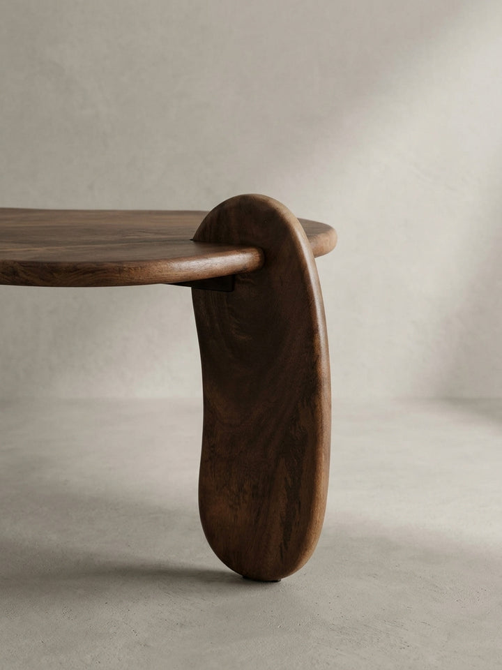 Eine weitere Perspektive des Mangoholz-Couchtisches, die die asymmetrische und fließende Designsprache des modernen Wohnzimmermöbels betont._