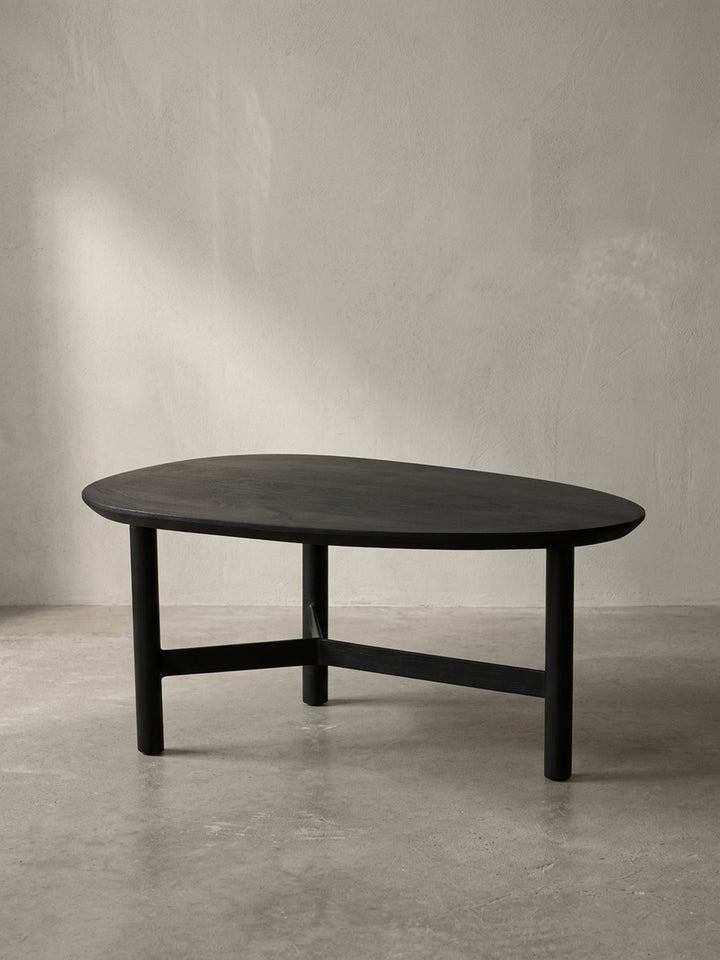 Gesamtüberblick des dreibeinigen Couchtischs in Schwarz, der das Zusammenspiel von massivem Mangoholz und pulverbeschichtetem Eisen in einem zeitlosen Design darstellt._