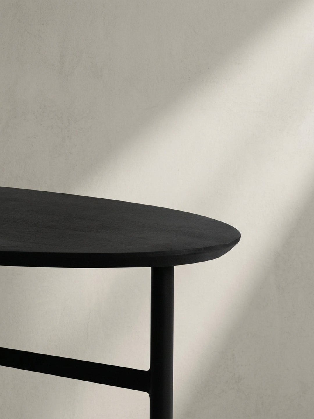 Niedriger Blickwinkel auf den schwarzen Couchtisch, der die dynamische Interaktion zwischen der geschwungenen Tischplatte und den geraden Beinen betont._