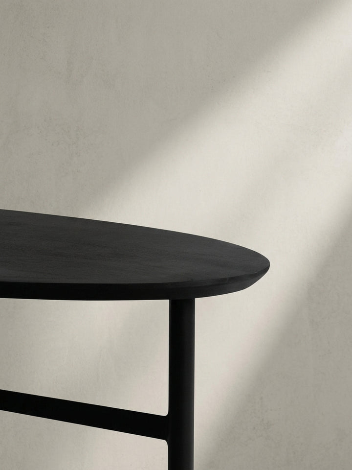 Niedriger Blickwinkel auf den schwarzen Couchtisch, der die dynamische Interaktion zwischen der geschwungenen Tischplatte und den geraden Beinen betont._