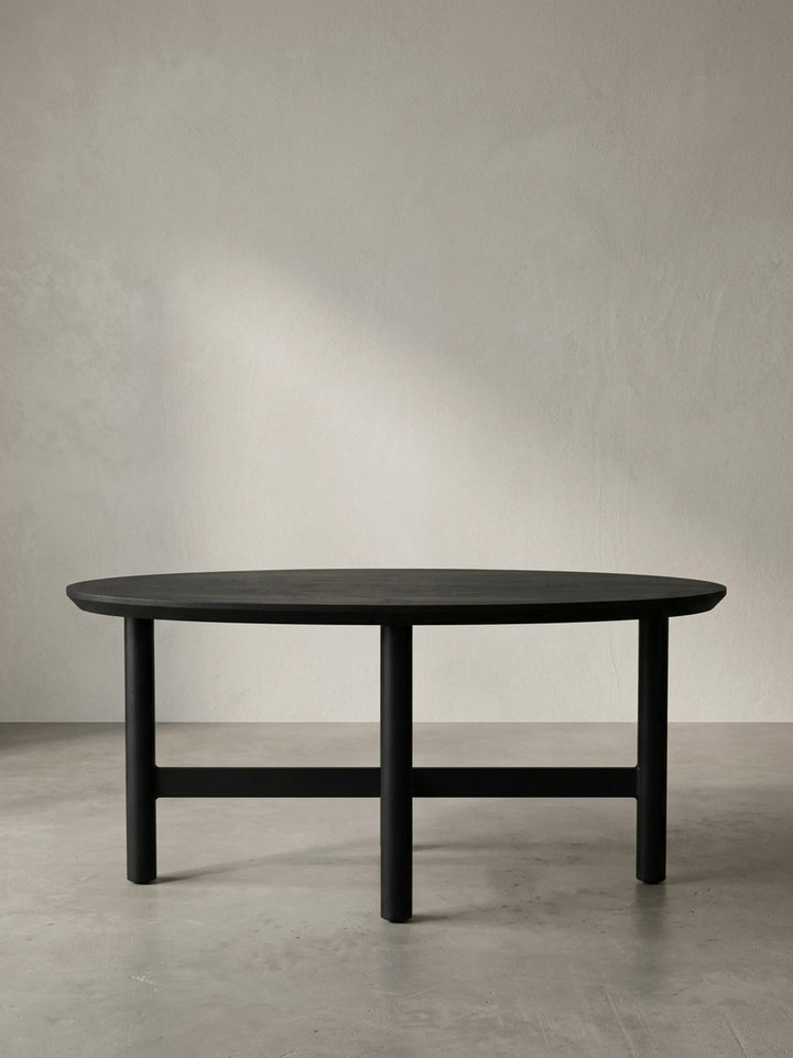 Schräge 3/4-Ansicht des schwarzen Sofatischs, die die elegante Linienführung der organischen Tischplatte und die stabile dreibeinige Metallkonstruktion hervorhebt._