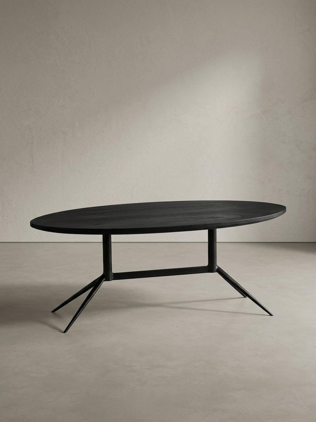Sofatisch 90x50 cm in Schwarz von schräg vorne mit Fokus auf die elegante ovale Form und die abgewinkelten schmalen Metallbeine_