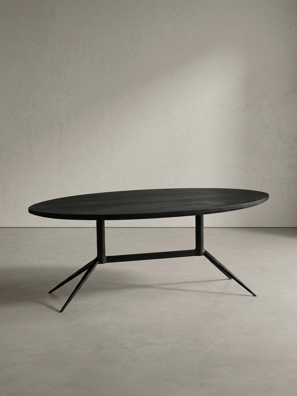 Sofatisch 90x50 cm in Schwarz von schräg vorne mit Fokus auf die elegante ovale Form und die abgewinkelten schmalen Metallbeine