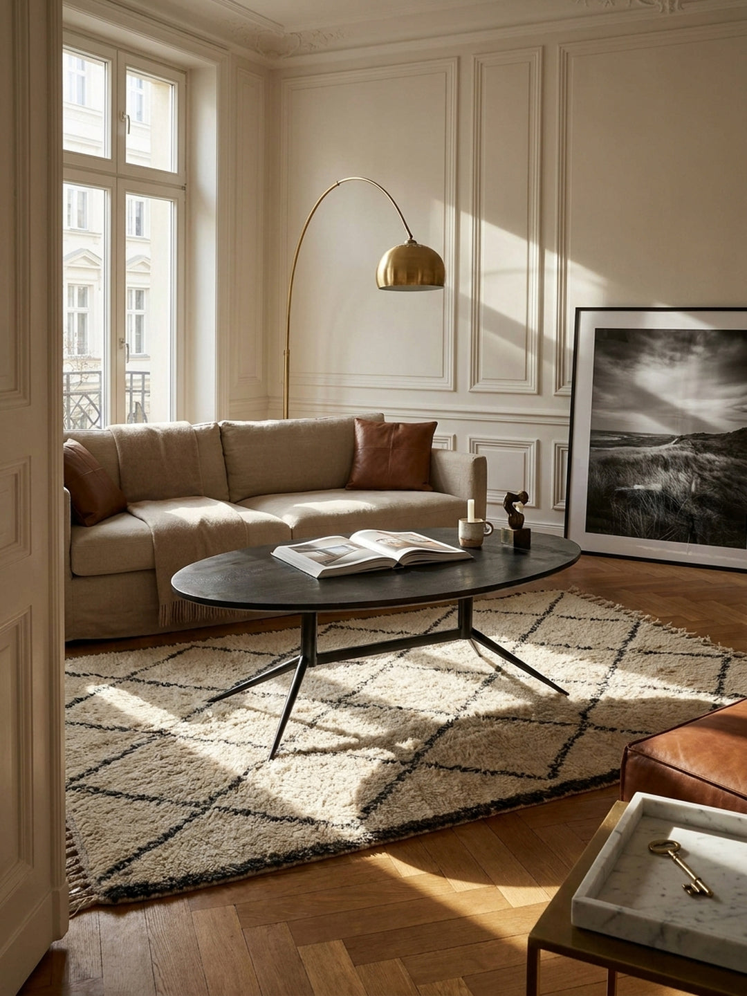 Eleganter Couchtisch oval aus massivem schwarzem Mangoholz vor hellem Leinensofa auf einem strukturierten cremefarbenen Wollteppich in einem modernen Wohnzimmer_