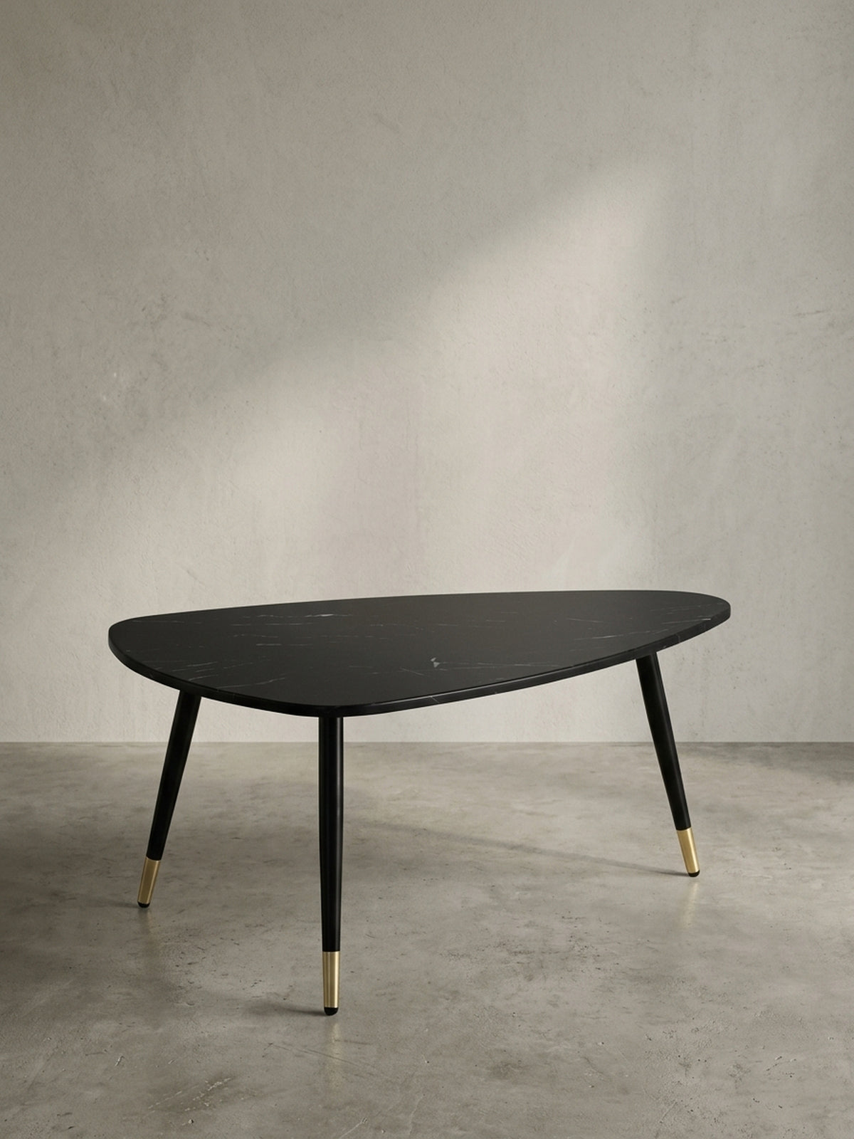 Gesamtübersicht des dreieckigen Wohnzimmertisches 90x60x41 cm, der eine stilvolle Balance aus schwarzer Steinoptik und warmen Messingdetails bietet.