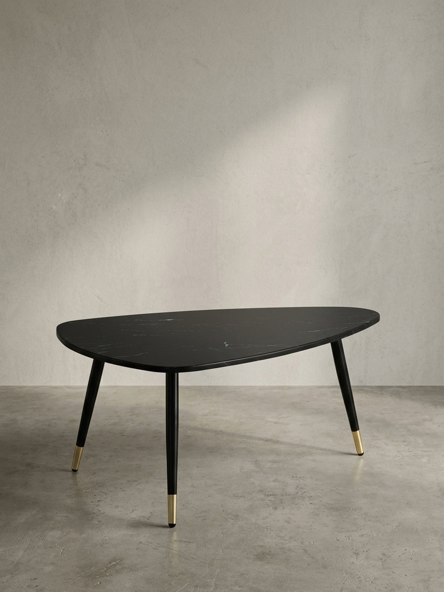 Gesamtübersicht des dreieckigen Wohnzimmertisches 90x60x41 cm, der eine stilvolle Balance aus schwarzer Steinoptik und warmen Messingdetails bietet._