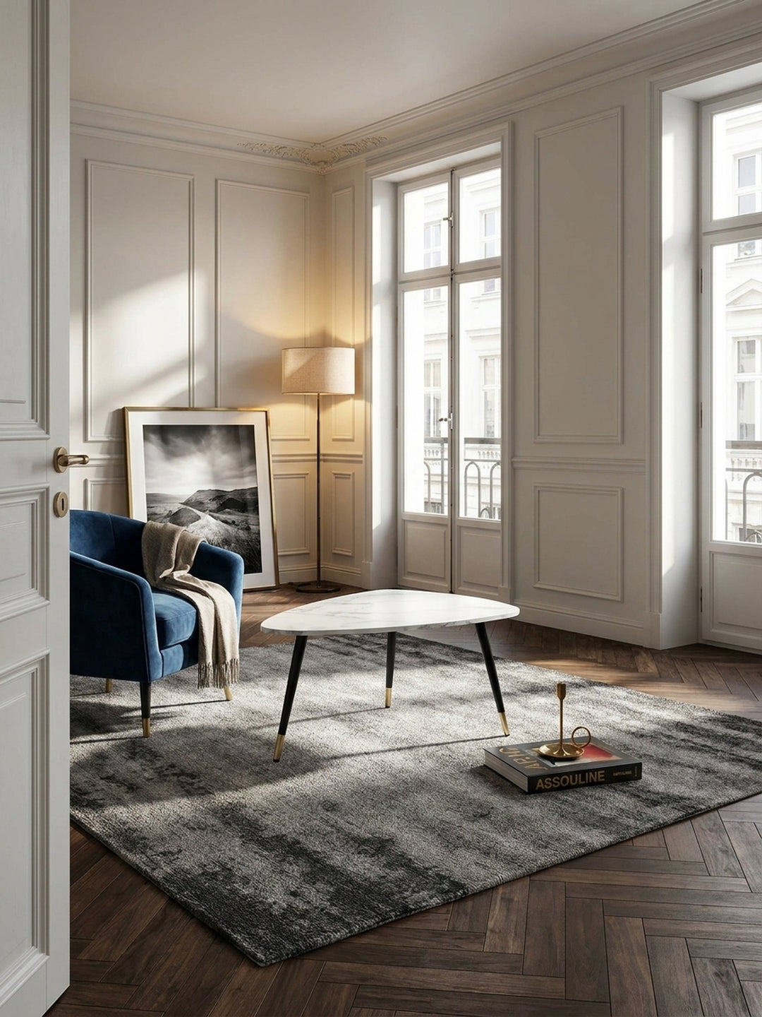 Eleganter Couchtisch in weißer Marmor-Optik auf dunklem Fischgrätparkett in einem stilvollen Pariser Wohnzimmer mit hohen Decken._