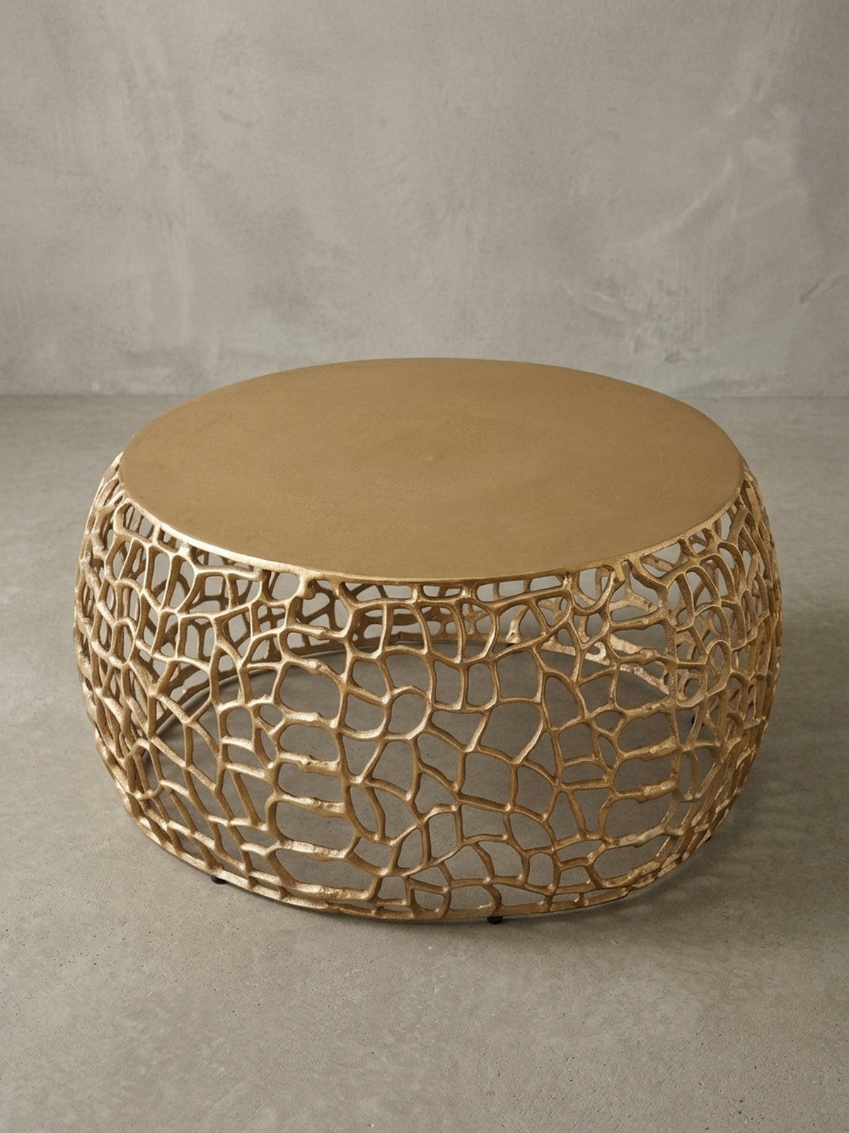 Makroaufnahme des Randes der 55 cm Tischplatte des goldenen Couchtischs, die den Übergang von der glatten Oberfläche zur organischen Basisstruktur betont._