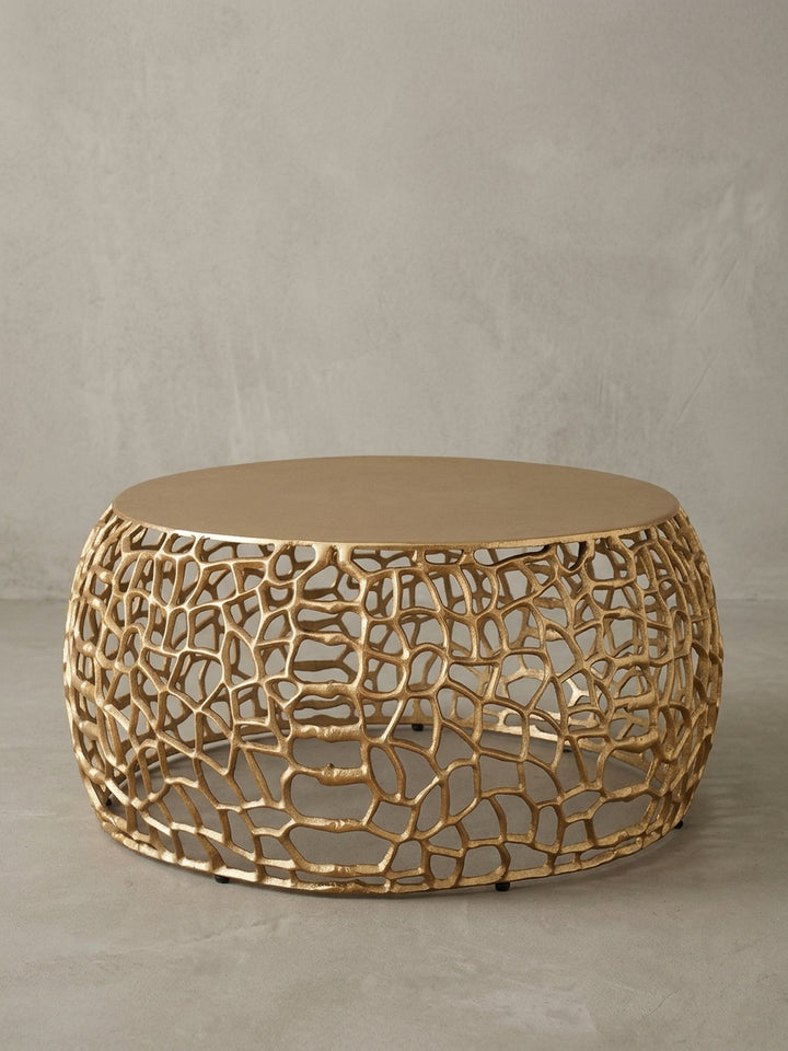 Schräge 3/4-Ansicht des modernen Wohnzimmertischs aus goldfarbenem Aluminium, die die dreidimensionale Tiefe der filigranen, durchbrochenen Ast-Struktur zeigt._