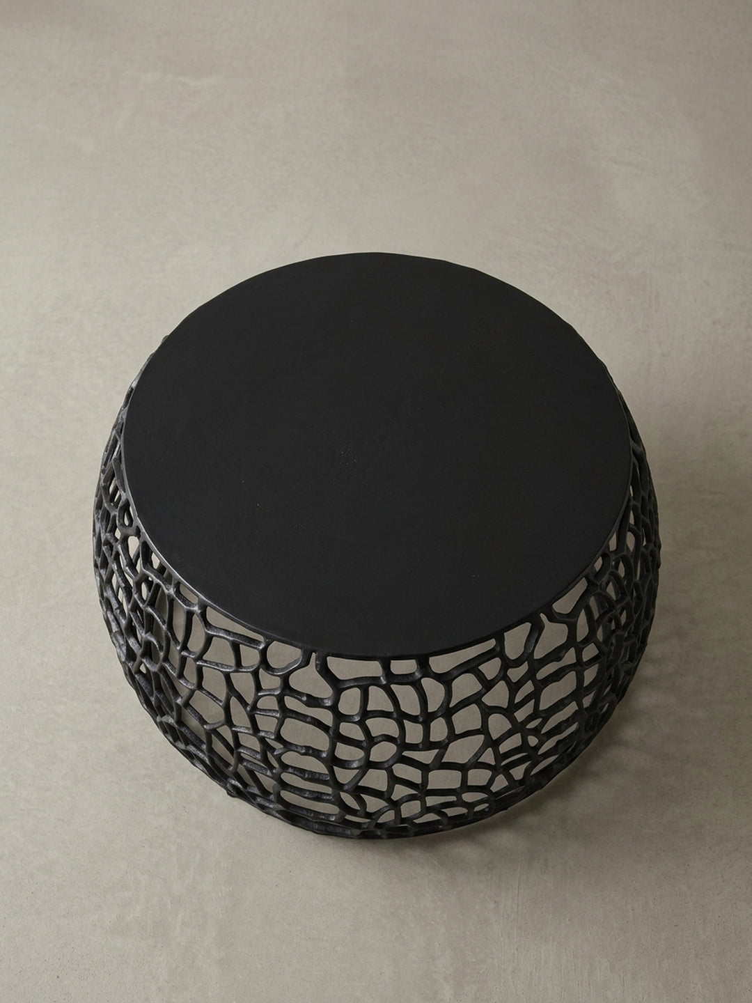 Alternativer Blickwinkel auf den schwarzen Aluminium-Sofatisch, der die skulpturale Qualität des runden Design-Wohnzimmertischs hervorhebt._