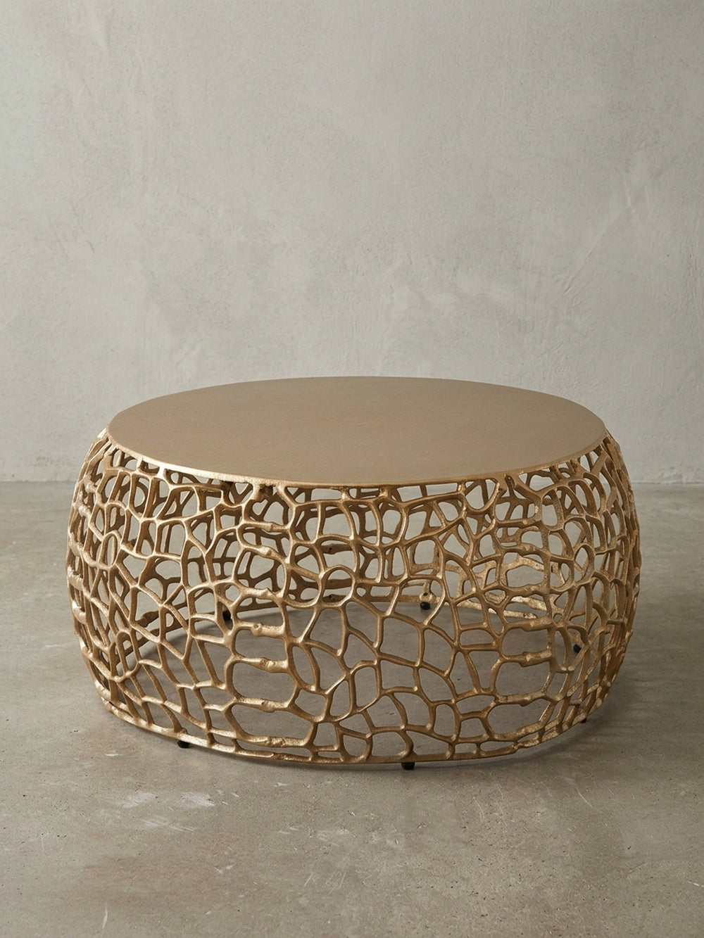 Frontansicht des runden Couchtischs in Gold, 66 cm breit, auf weißem Hintergrund, der die organische, astähnliche Basis und die massive Tischplatte klar darstellt._