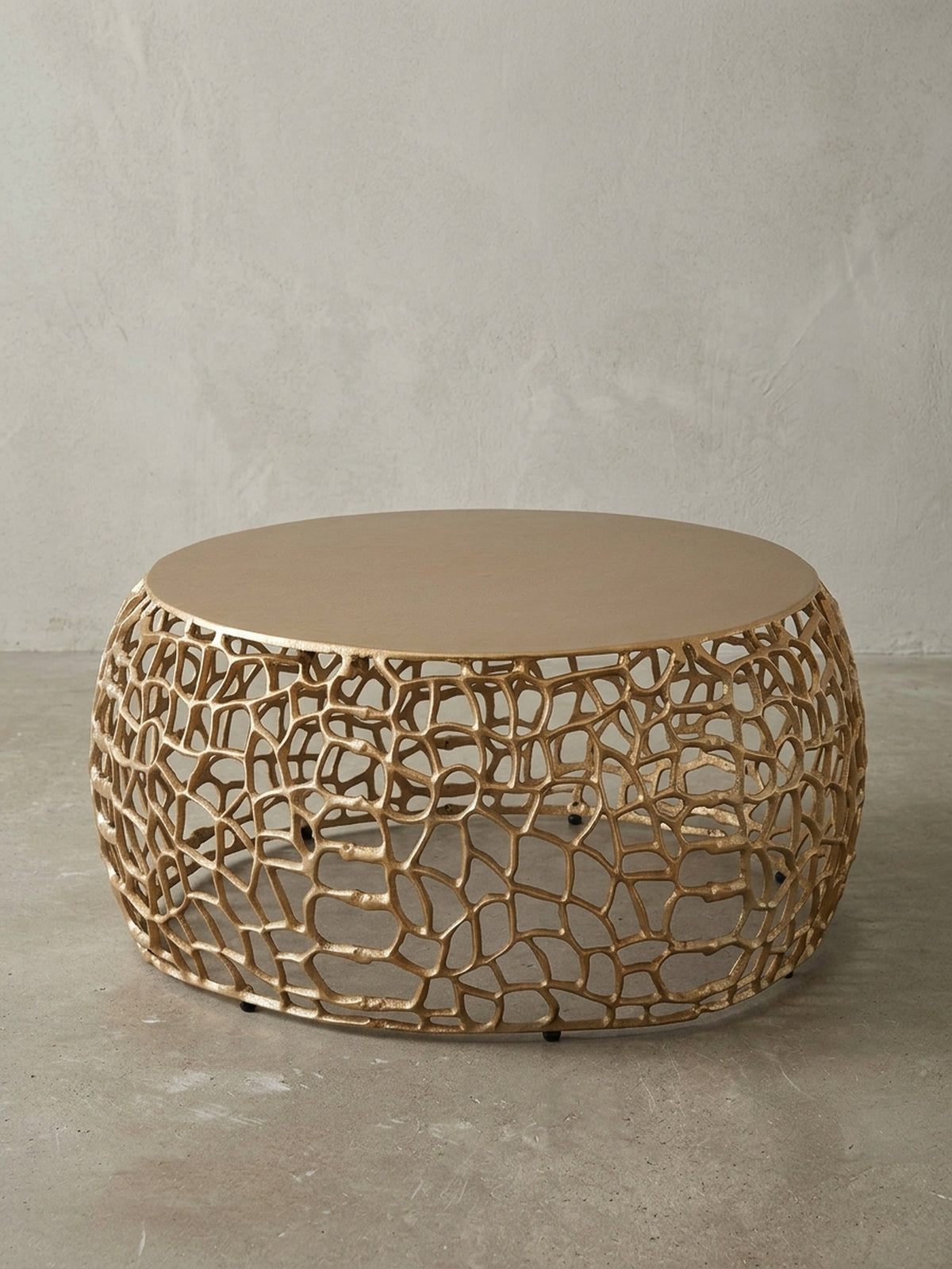 Frontansicht des runden Couchtischs in Gold, 66 cm breit, auf weißem Hintergrund, der die organische, astähnliche Basis und die massive Tischplatte klar darstellt._