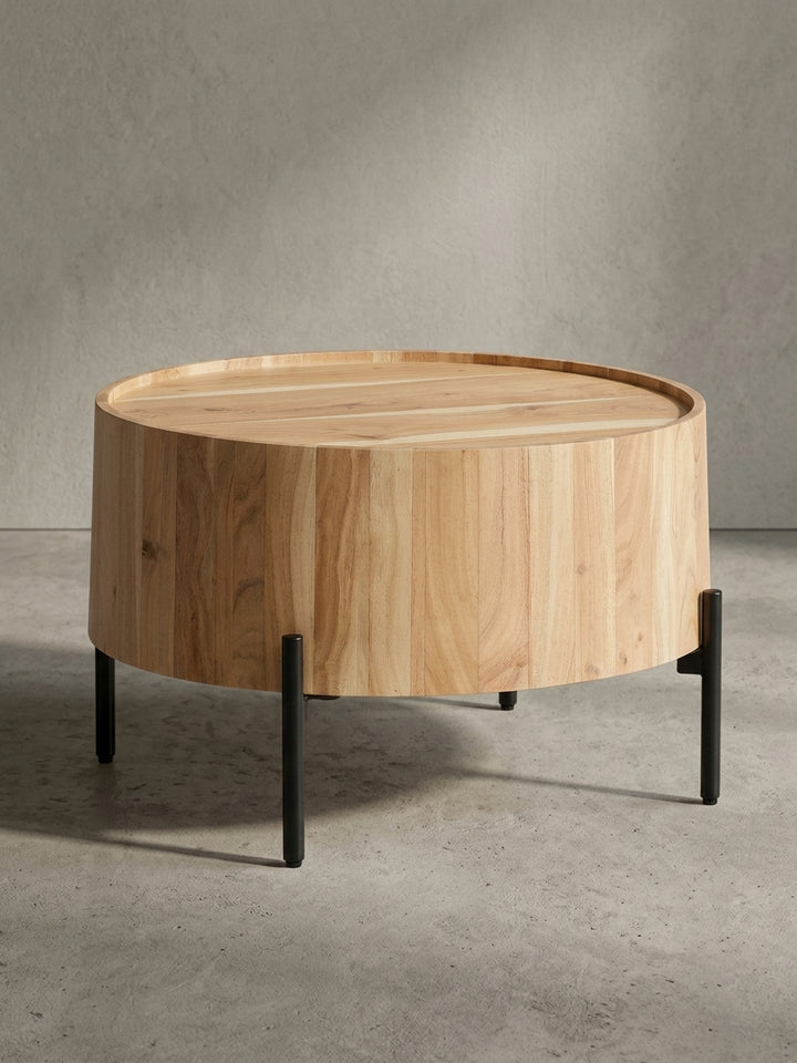 Nahaufnahme des Übergangs vom massiven Akazienholz-Korpus zu einem der pulverbeschichteten Metallbeine, die die hochwertige Verarbeitung des Sofatisches zeigt._