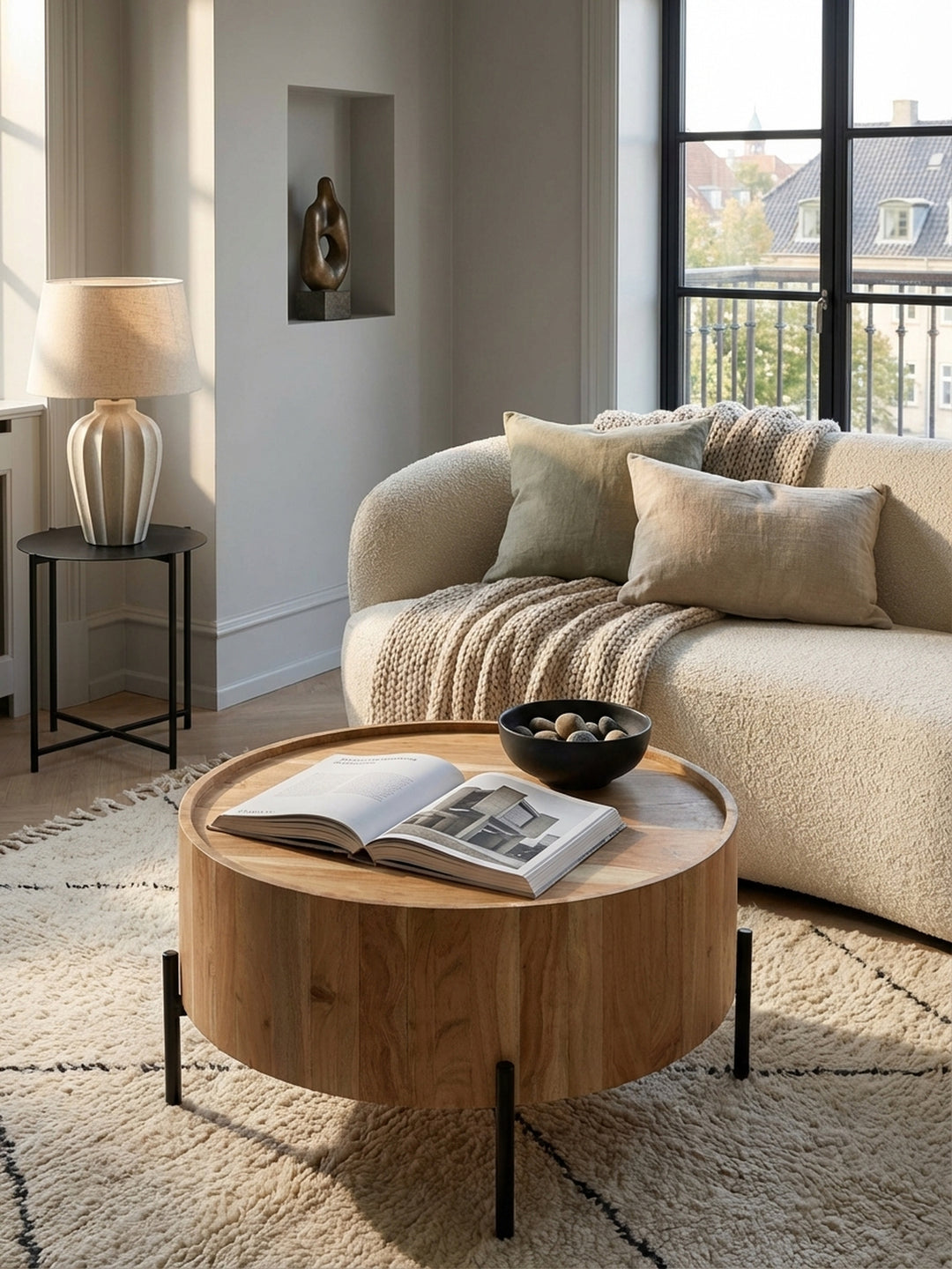 Der kompakte Sofatisch aus Akazienholz mit schwarzen Metallbeinen ergänzt ein dunkles Ledersofa und einen hellen Teppich zu einer stilvollen Sitzgruppe._