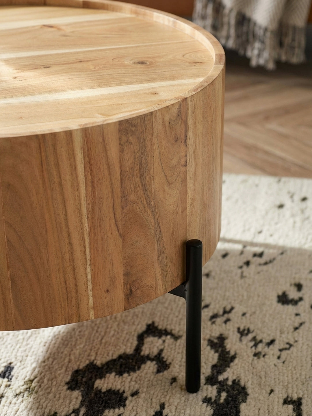 Detailaufnahme der markanten Maserung des massiven Akazienholzes des Couchtisches, dessen Oberfläche mit einem schützenden Klarlack veredelt wurde._