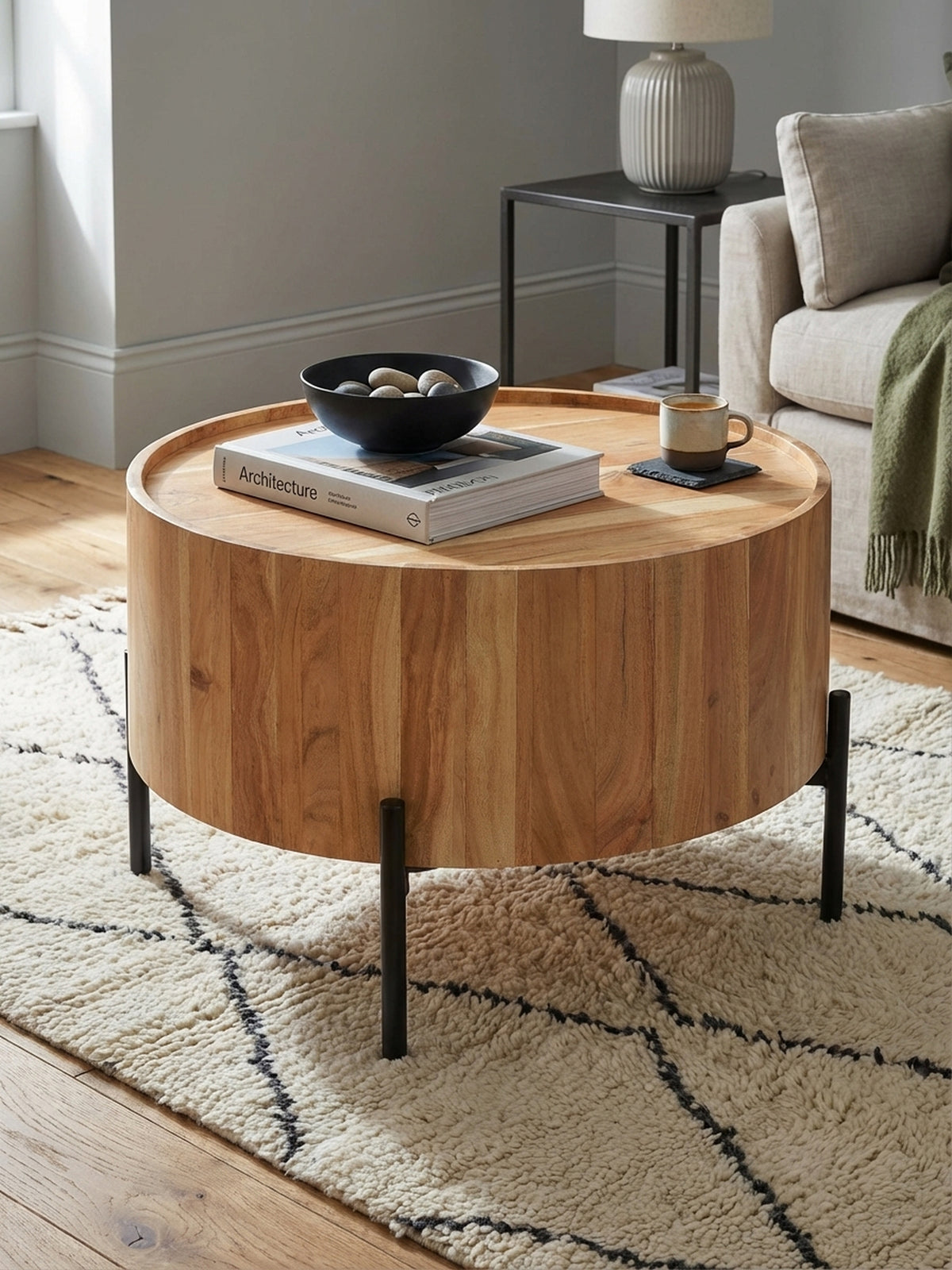 Ein Stapel Bücher und eine Glasvase mit Trockenblumen schmücken den modernen Massivholz-Couchtisch und schaffen eine gemütliche Atmosphäre im Wohnzimmer.