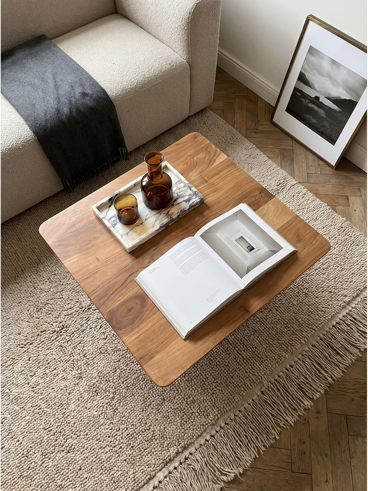 Draufsicht auf den 60x60 cm Couchtisch mit natürlicher Holzmaserung vor einem beigen Bouclé-Sofa im modern-klassischen Wohnbereich._