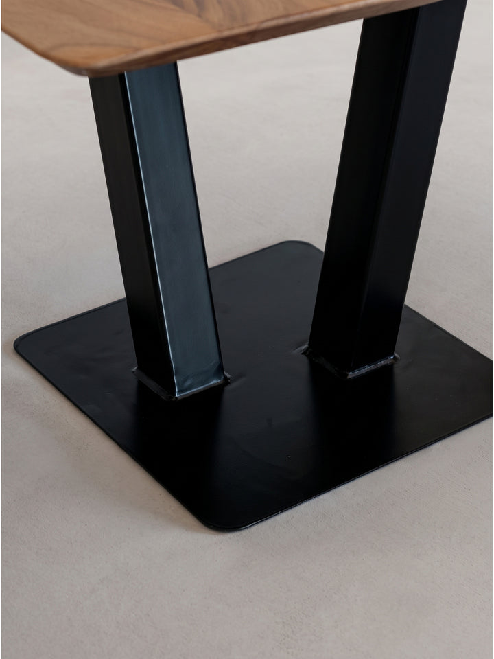 Schräge Studioperspektive des 60x60 cm großen Holztisches veranschaulicht die symmetrische Geometrie des zentralen Metallfußes._