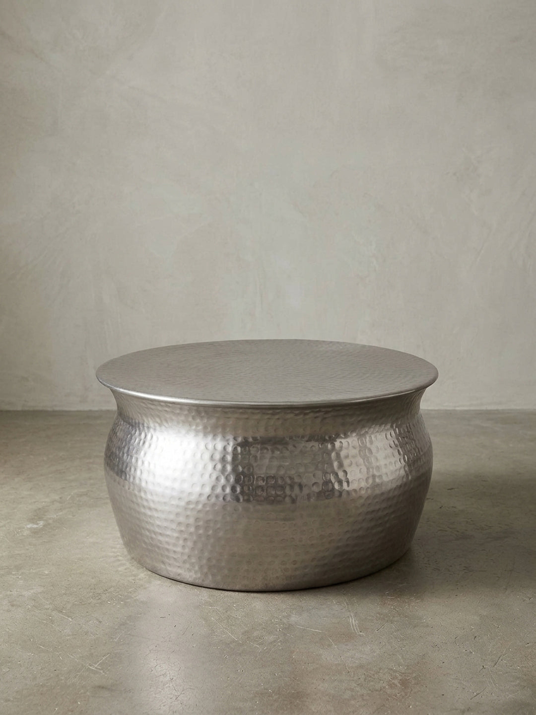 Runder Couchtisch 60x30,5x60cm aus silbernem Aluminium in Frontalansicht. Der flache Wohnzimmertisch besticht durch seine bauchige Silhouette und die markante Hammerschlag-Optik._