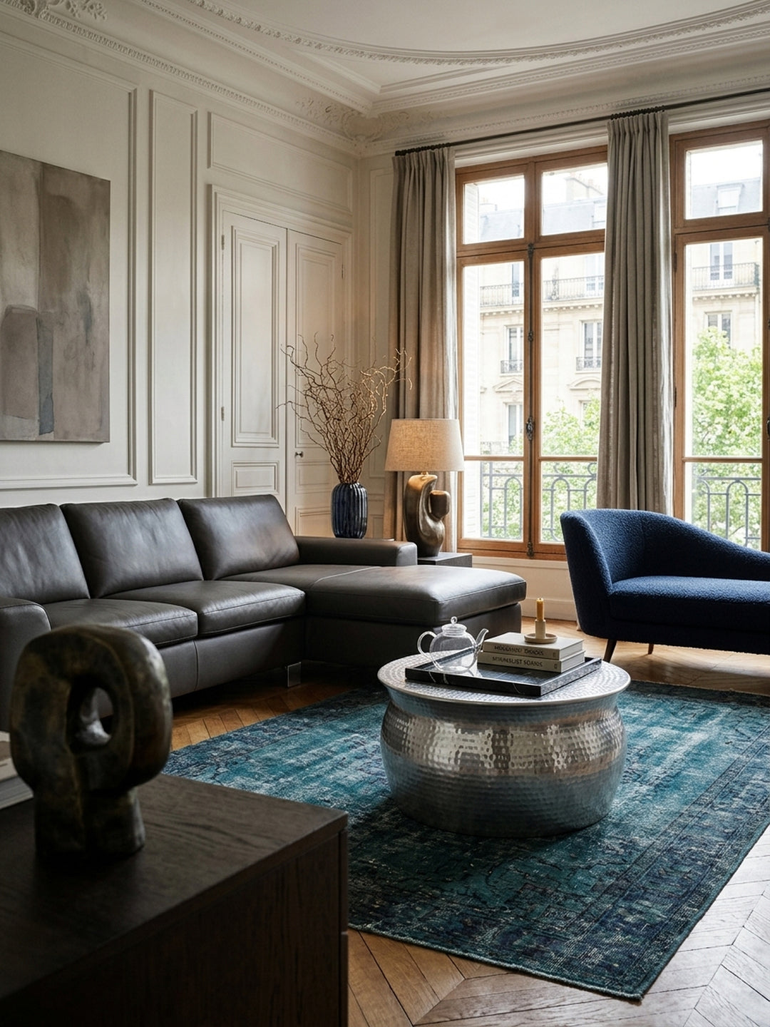 Eleganter runder Couchtisch aus silbernem Aluminium in einem luxuriösen Wohnzimmer. Das bauchige Design mit Hammerschlag-Optik (60x30,5cm) reflektiert sanft das Tageslicht._