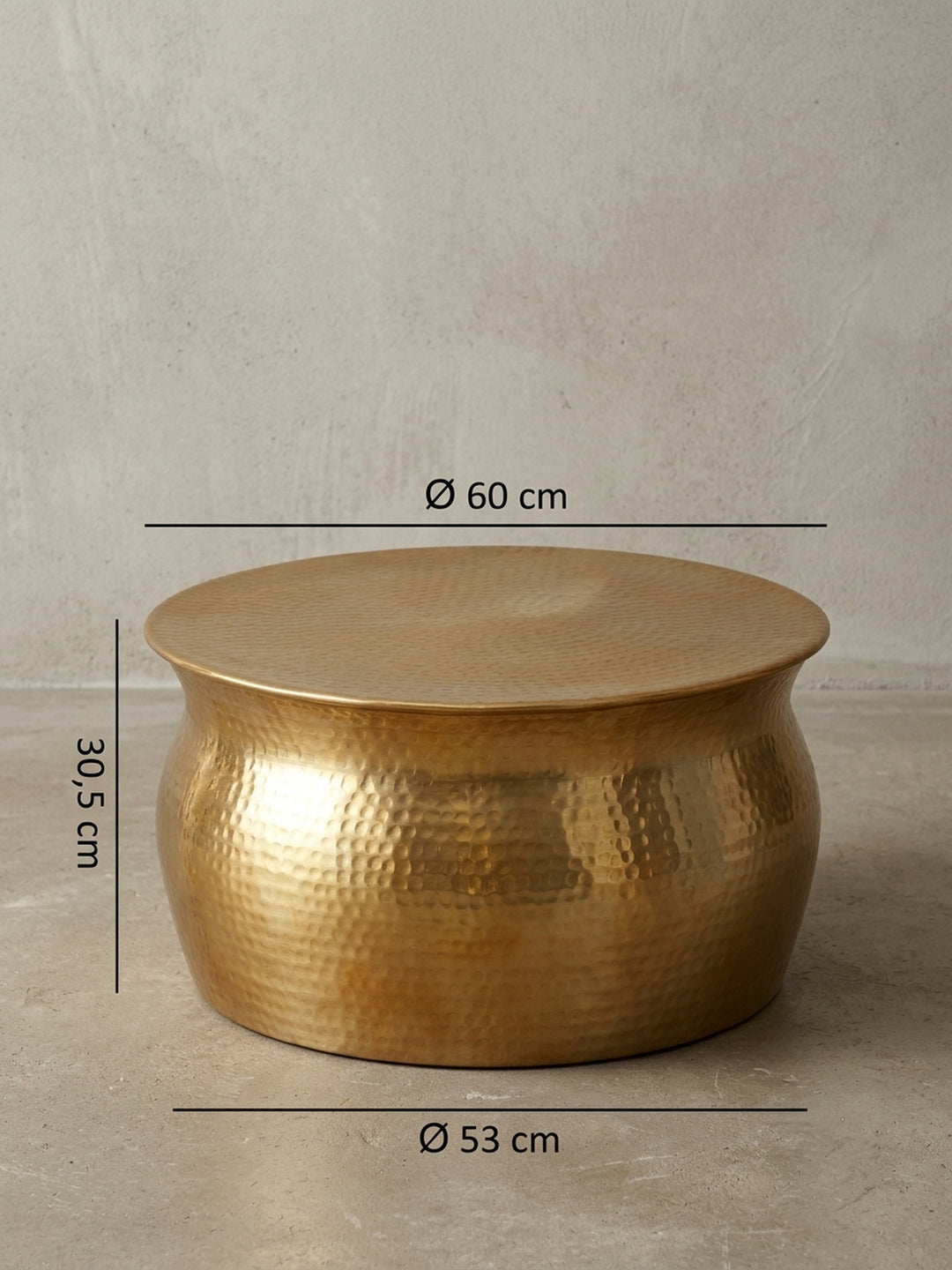 Detailansicht der Rückseite des bauchigen Metalltisches. Der rund geformte Wohnzimmertisch in schimmerndem Gold präsentiert die nahtlose Verarbeitung des gehämmerten Aluminiums._