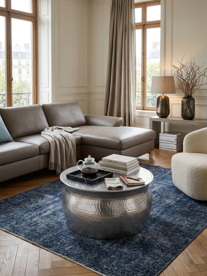 Draufsicht auf einen flachen Metall-Sofatisch in Silber. Die strukturierte Oberfläche des 60x60cm großen Loungetisches bildet einen stilvollen Kontrast zum dunklen Vintage-Teppich._