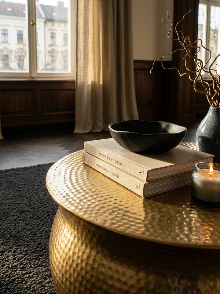 Nahaufnahme der handgefertigten Hammerschlag-Struktur des goldenen Couchtisches. Das lackierte Aluminium des orientalischen Beistelltisches zeigt eine edle, unregelmäßige Oberfläche._