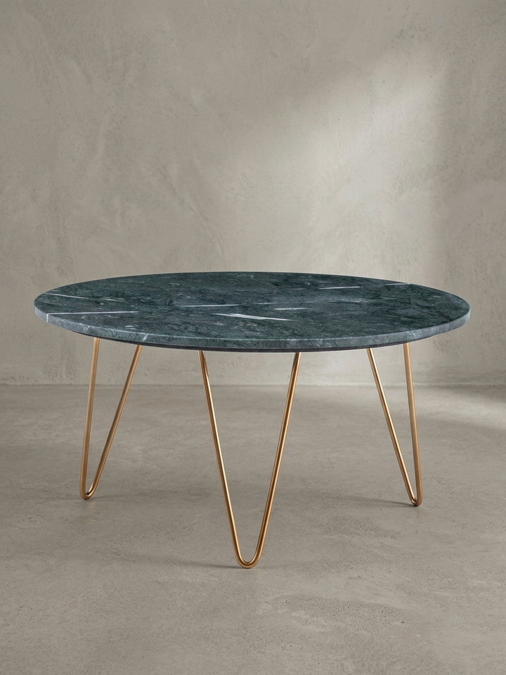 Dreiviertelansicht des Designer-Couchtisches, die die elegante Verbindung der goldenen Metallbeine mit der massiven, grünen Marmorplatte hervorhebt._