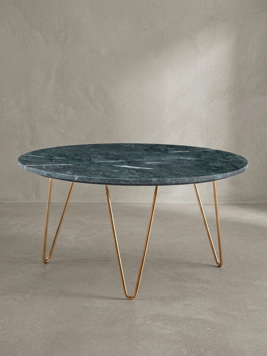 Dreiviertelansicht des Designer-Couchtisches, die die elegante Verbindung der goldenen Metallbeine mit der massiven, grünen Marmorplatte hervorhebt._