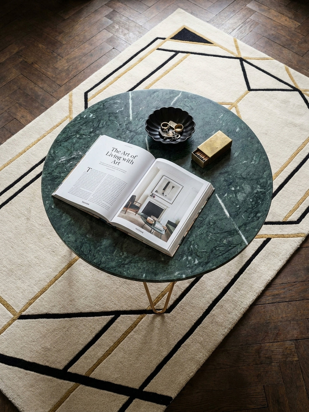 Draufsicht auf den runden Couchtisch aus echtem Marmor, arrangiert auf einem Art-Deco-Teppich neben einem Sofa, die harmonische Komposition des Wohnbereichs zeigend._