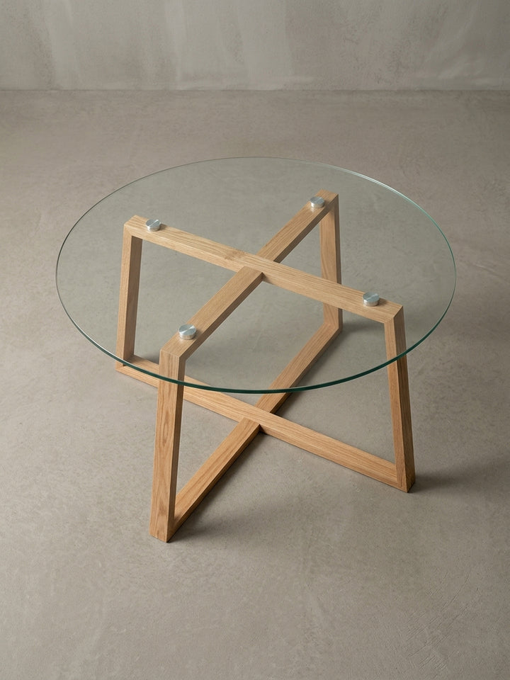 Alternativer Blickwinkel auf den Glastisch für das Wohnzimmer, fokussiert auf die Kombination aus der transparenten Platte und dem warmen Eichenholz._